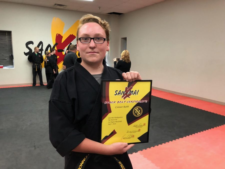 Sophomore Connor Robb holding up his certificate moments after passing the black belt exam.