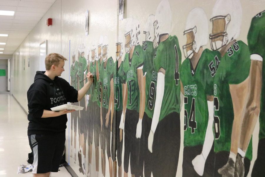Using a steady hand, senior Adrian Judson paints details on the players jerseys. Judson worked for about 100 hours on the mural. 