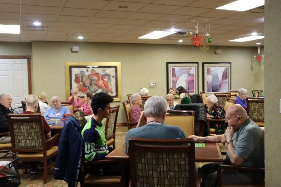 Junior Rami Hanash plays bingo with residents at Walnut Grove Retirement Community. Millard West Student Council visits there frequently and this year they also held a Halloween Bingo. They absolutely love seeing our faces and talking to us, senior and Student Council president Olivia Oeth said. We bring a good variety of people there to interact with the residents.