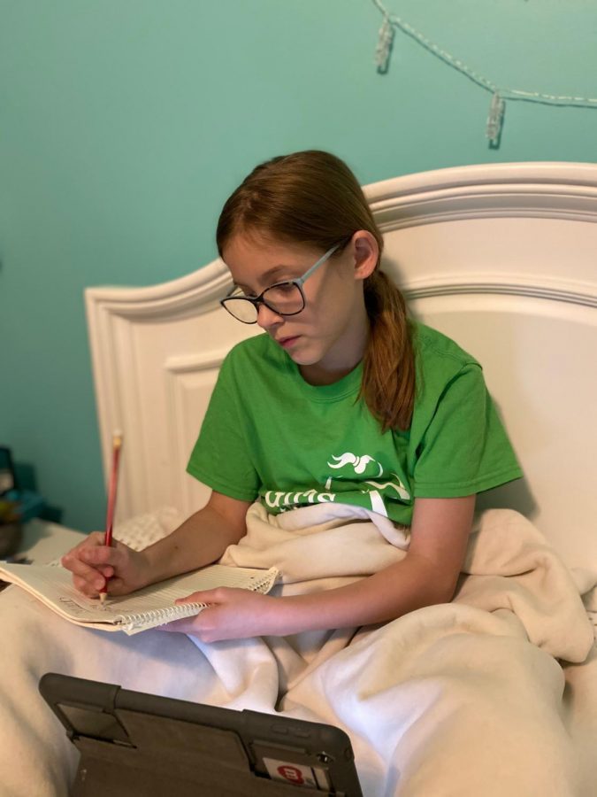 Fifth grader Anna Jetter sits in her bed and does her online learning. She has missed her friends and teachers during her time away from school.