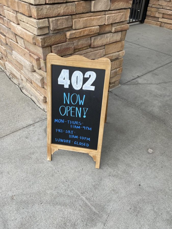 402 Eat + Drink opened August 11th . This sign sits outside on their front door step giving the hours and operations for the restaurants and welcoming the customers in. 