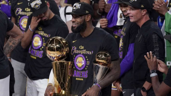 Laker forward LeBron James holds his fourth Larry O’Brien trophy and Finals MVP award. James is the only player in the four major American sports (Football, Baseball, Basketball, Hockey) to win a playoff MVP award with three different teams. “I’ve got a lot of years left in the tank,” said James, who is 35 years old and in his eighteenth season. “I’m still at the top of my game.”
