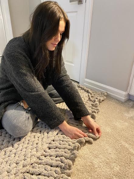 Senior Paige Stobbe adds to her current creation with another row of chunky yarn. She has been hand-knitting these trendy blankets to sell during the holidays. “There has been quite a shortage in yarn lately,” Stobbe said. “That is one challenge that I have run into, but I hope to keep it going.”
