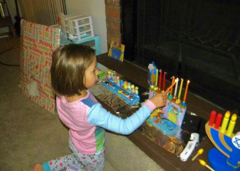 A+young+Friedland+lights+her+hanukkiah.+%E2%80%9CI+was+raised+Jewish+so+I+have+celebrated+it+%5BHanukkah%5D+since+I+was+a+baby%2C%E2%80%9D+junior+Abby+Friedland+said.+%E2%80%9CHanukkah%2C+to+me%2C+is+just+family+time%2C+like+many+who+celebrate+Christmas.+It%E2%80%99s+a+good+way+to+feel+connected+to+those+around+you.%E2%80%9D