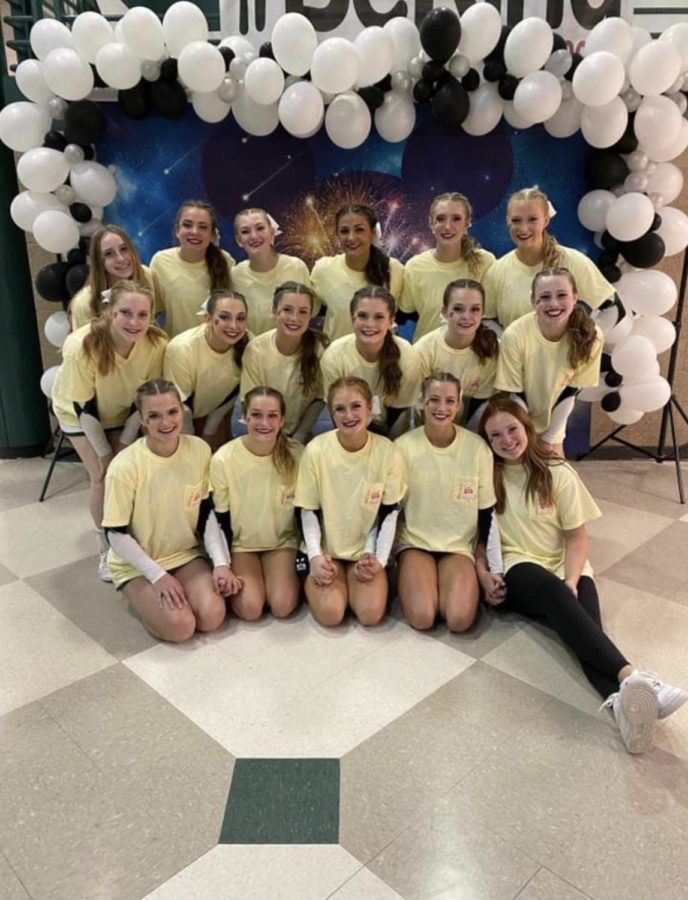 The varsity Competition cheer team poses in front of a banner they created to resemble the Disney feel that they typically would get at an in-person competition.

