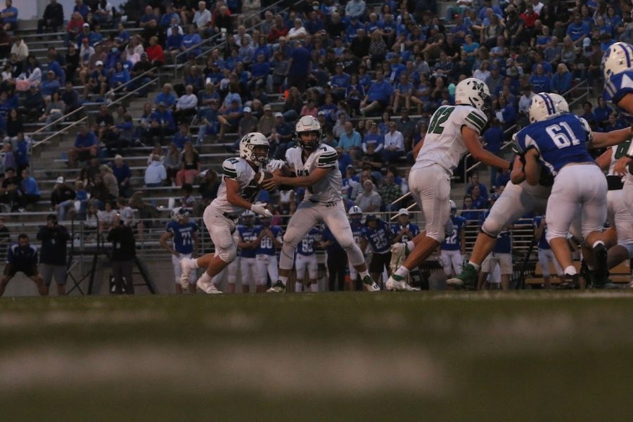 Sophomore Brody Peterson hands the ball of the senior Nathan Pederson against the Lincoln East Spartans. The Spartans won 41-10.