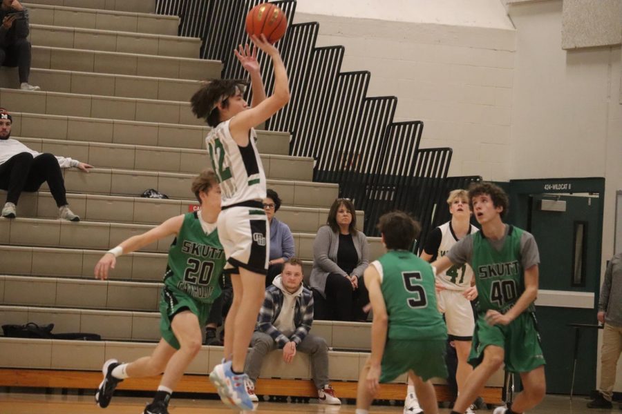 Sophomore Brady mar Shoots a three-pointer with Skutt defenders closing in. 