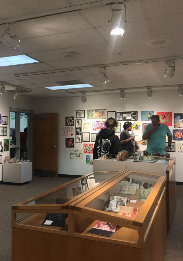 Art students walk around the art gallery showcasing their work to their friends and family.