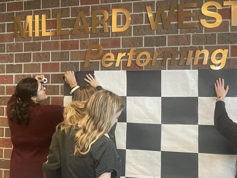 Members of the publicity crew hanging up a checkerboard in the auditorium lobby. It will be used as a backdrop for photos when “Clue” premiers Dec. 1-3. “This process has definitely been on the harder side due to the short amount of time we have to pull it off,” Publicity crew co-leader and junior Ali Gardener said. “There are only six weeks to pull off Clue so it has been a struggle trying to get everything ready and come up with ideas to sell as many tickets as fast as possible.”