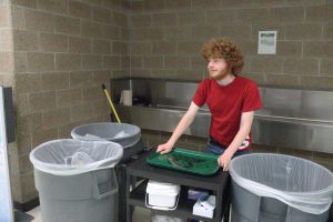 Stacking dirty lunch trays, junior Carson Chesterman keeps the conveyor belt to the dish washing center running smoothly during second lunch. Although a simple task, it provides some major help and a much needed break for the custodial staff to focus on other areas of the cafeteria. “I enjoy seeing my fellow peers also taking on the responsibility of cleaning and helping out around the school as well,” Chesterman said. “I firmly believe that it is everyone’s responsibility to help others out, one way or another.” Photo by Kelsey Nunnenkamp 
