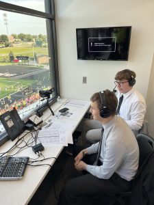 In the press box at Buell Stadium, Nathan Delaney and Logan Moseley commentate over a Wildcat football game.
