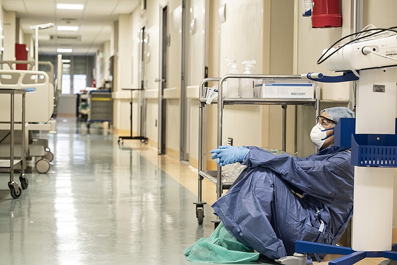 A nurse taking their break after a 12 hour shift in an empty hallway during the peak months of COVID-19.